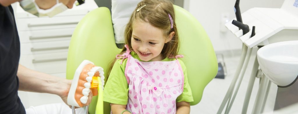 A pediatric dentist talking to a child patient.